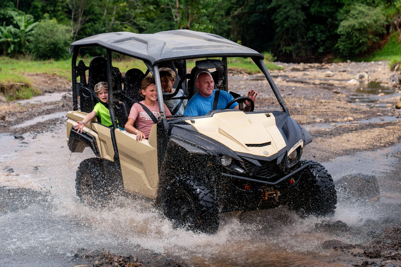 Family riding a buggy across a river